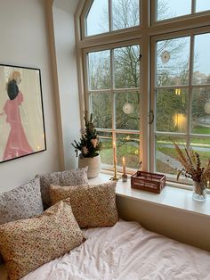 a bedroom with a large window and a bed in front of the window is filled with pillows