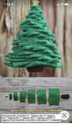 a green christmas tree ornament hanging from a wooden board with thread and needles