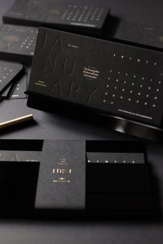 several black business cards with gold foil on them and one has a pen in the middle