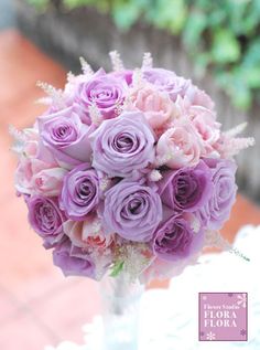 a vase filled with purple flowers sitting on top of a white lace covered table cloth