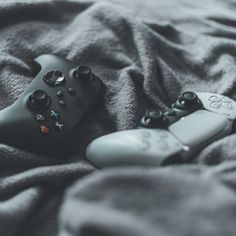 two video game controllers laying on top of a blanket