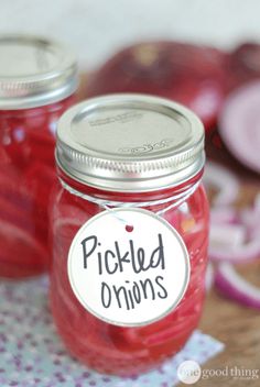 two jars filled with pickled onions on top of a table