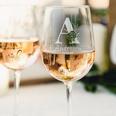 two wine glasses sitting next to each other on top of a white tablecloth covered table