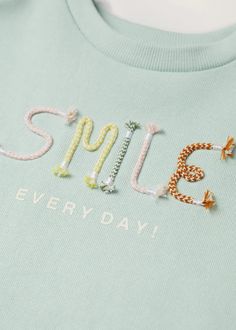 a t - shirt with the words smile on it and beaded letters in different colors