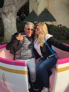 two people sitting in a pink and white bench