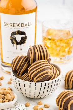 chocolate covered peanut butter balls in a bowl next to a bottle of whiskey and peanuts