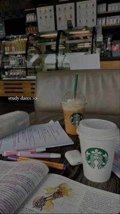 there is a cup of starbucks coffee next to an open book