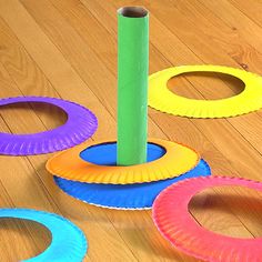 colorful paper plates on the floor with a green stick sticking out of one hole in the middle