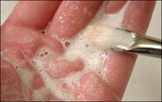 a person holding a toothbrush in their left hand with soapy water on it