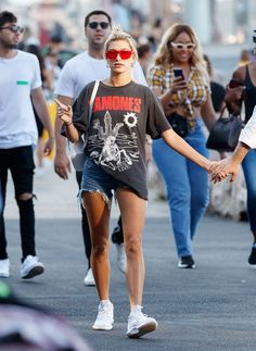 a woman walking down the street holding hands with another person wearing red sunglasses and an armband