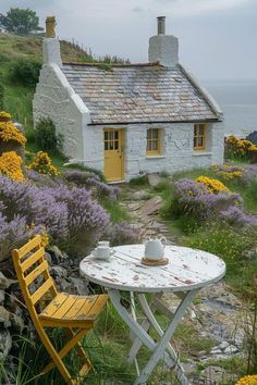 a table and chair sitting in front of a small house on the side of a hill