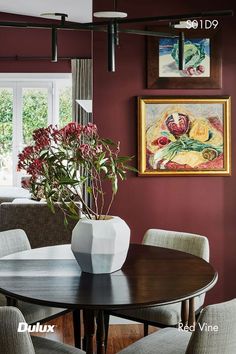 a dining room table with chairs and a vase filled with flowers on top of it