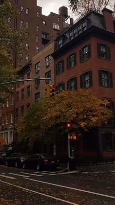 a red traffic light sitting on the side of a road next to tall buildings and trees