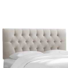 a bed with white sheets and pillows in front of a headboard that has buttons on it