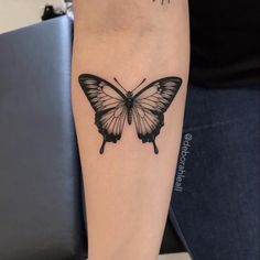 a black and white butterfly tattoo on the arm