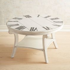 a white coffee table with roman numerals on the top and bottom part, sitting on a hard wood floor