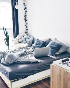 a bed with lots of pillows on top of it and a laptop in the middle