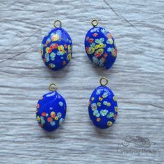 "These 1980's vintage glass drops were made in Japan. They feature a puffy oval shape with a multicolored millefiori pattern. The base color is a vibrant opaque royal blue, and the flowers are a mix of white, red and yellow. MATERIALS, MEASUREMENTS & QUANTITIES ✭ Material = glass ✭ Pendant size = 15x21 mm by approx 7mm deep ✭ Quantity = 4 pieces These funky little drops measure just under 1\" long, including the gold toned metal loop. It's a nice mid size that's well suited to earrings or pe Multicolor Flowers, Glass Charms, Mid Size, Oval Pendant, 1980s Vintage, Beading Supplies, Etsy Shipping, Vintage Japanese, Gold Tone Metal