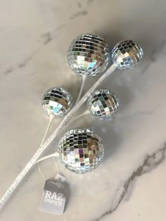 four disco ball lights on a white marble counter top with a tag that says dazzle house