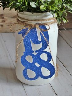 a white mason jar with blue and white painted numbers on it, tied with twine