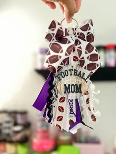 a person holding up a football mom ribbon