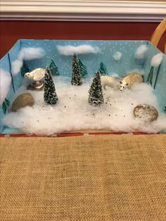 a snow scene with polar bears and pine trees in a blue box on a table