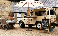 a food truck parked in front of a building with an umbrella over it's head