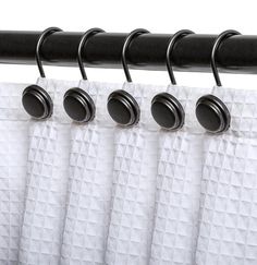 black and white curtains hanging on the side of a curtain rod with four round knobs