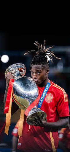 a soccer player holding a trophy and wearing dreadlocks