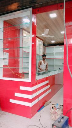 a man standing in the window of a red and white building with lots of shelves