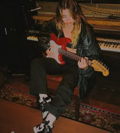 a woman sitting in front of a piano playing an electric guitar