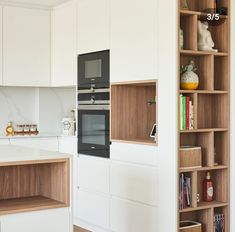 a kitchen with an oven, microwave and bookcases on the wall next to it