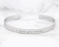 "Valentine's Day Bracelet * I Love You More Cuff Bracelet A beautiful and sturdy (14 gauge) solid aluminum cuff bracelet is precision laser engraved with your custom text! Create a very special and meaningful personalized Valentine's Day gift with our custom bracelet. The width of the aluminum cuff is 1/4\" and is engraved with the text \"i love you more\" but can also be personalized with up to about 35 characters. If no custom text is requested, the bracelet will be sent with the text pictured Bible Verse Jewelry, Motivational Bracelets, Motivational Jewelry, Handwriting Bracelet, Dream Bracelet, Engraved Cuff, Bracelet Quotes, Peoria Az, Pins Board