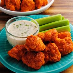 a blue plate topped with tater tots next to celery sticks and dip