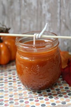 a glass jar filled with liquid sitting on top of a table next to pumpkins