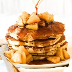 a stack of pancakes with syrup being poured on top