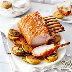 a plate topped with meat and potatoes on top of a table next to utensils