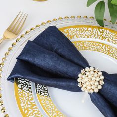 a white plate topped with blue napkins and gold place settings