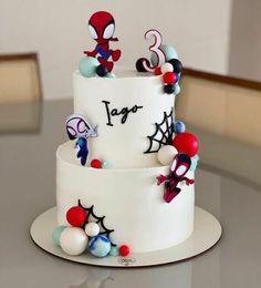 a three tiered cake decorated with spiderman decorations