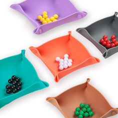 four plastic trays with different colored balls in them