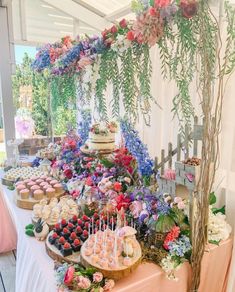 a table topped with lots of cakes and cupcakes next to a tall tree