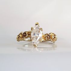 a gold ring with an oval cut diamond in the center and filigrees on each side