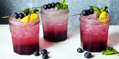 three glasses filled with blueberry lemonade and garnished with fresh mint leaves