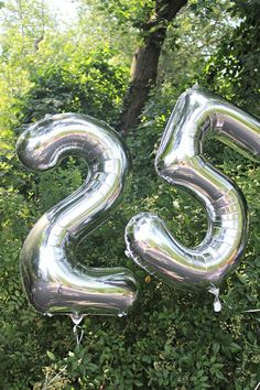 the number twenty five balloon is in front of some trees