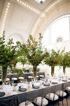 the tables are set with flowers and greenery in vases on top of them