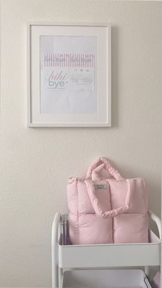 a pink purse sitting on top of a white chair in front of a framed picture