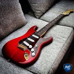 a red guitar sitting on top of a couch