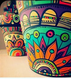 three brightly colored pots sitting on top of a table next to each other, with designs painted on them