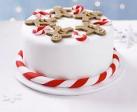 a white cake with red and white striped icing is decorated with gingerbread men