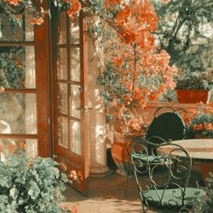 an outdoor table and chairs in the middle of a garden with red flowers on it